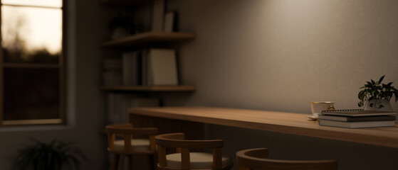 A wooden table with stools against the wall in a minimal cosy room in the evening with low lights.