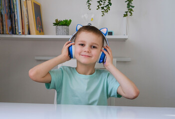 Portrait of funny boy listening to music on wireless headphones, enjoying his favorite songs....