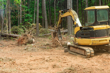 To prepare land for residential construction, excavators tractors are uprooting trees