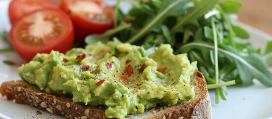 A dish made of a slice of bread topped with guacamole, plum tomatoes, and leaf vegetables on a plate as a plantbased food recipe