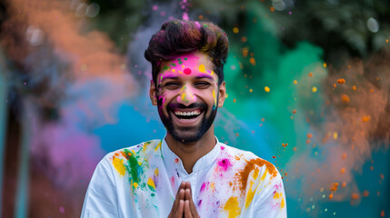 Photoshoot of a happy Indian man covered in colour, namaste gesture, holi celebration - obrazy, fototapety, plakaty