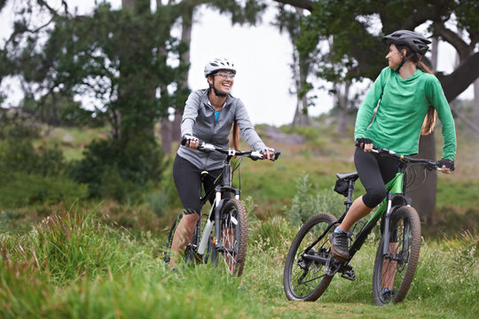 Happy woman, friends and fitness with bicycle on field for outdoor cycling, workout or cardio exercise in nature. Female person, athlete or cyclist with smile in forest for off road training on trail