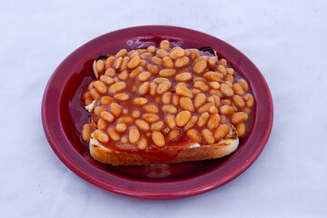 Baked beans in tomato sauce on a slice of white bread toast