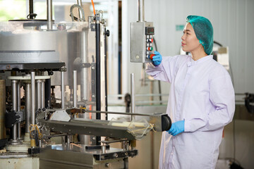 Naklejka premium female worker working on machine in the beverage factory