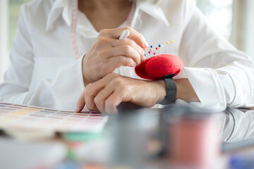 Asian designer women working at studio. Fashion designer carefully creating new fashionable styles. Dressmaker makes clothes job