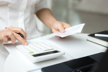 Woman using a calculator to calculate a credit card bill information at office