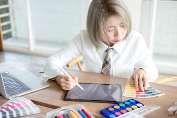 Graphic designer using color swatch to do his work at modern office. Architect using work tools and sample colour catalog.