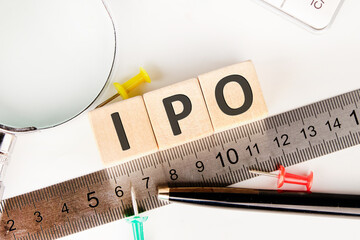IPO abbreviation of Initial Public Offering text of non-wooden cubes next to a calculator, pen,...