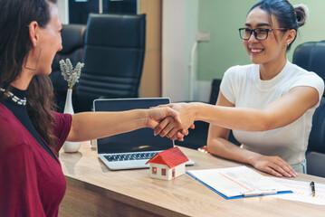 Businesswoman shakes hands with customer dealing real estate house agent signing contract. Team...