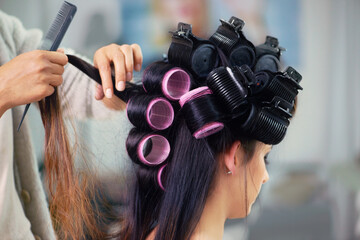 Woman, hair care and makeup with curlers and hands of stylist, cosmetic care and beautician with...