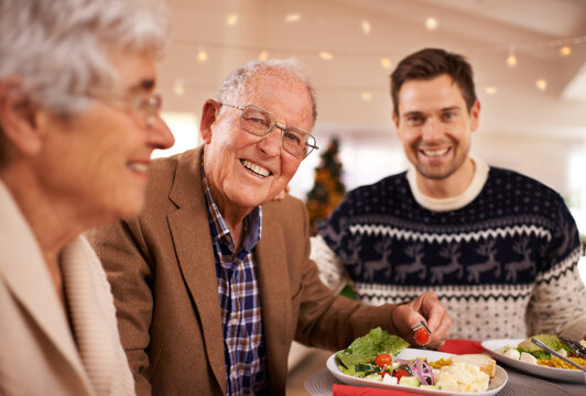 Grandfather, portrait and family at dinner on Christmas together with food and celebration in home. Happy, event and old man smile with plate at lunch and relax on holiday at table with people