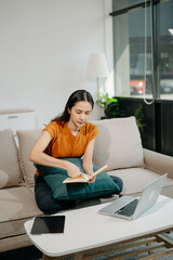 Woman sitting on sofa using a laptop computer Navigating Finance and Marketing with Technology in home office