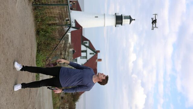 Content Creator Launching Drone From Hand With Portland Head Lighthouse In The Background. - vertical shot