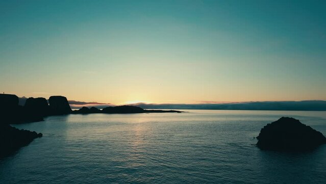 Incredible drone aerial of coral sea arch and coastal lands during sunset.  Gatklettur.  Hellnar Arch Iceland.  The camera passes through the arch.