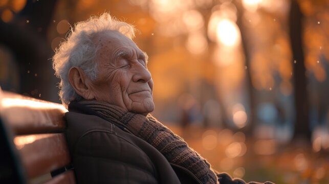 An elderly man sitting on a park bench his eyes closed and a faint smile on his face as he listens to the birds singing and the gentle hum of a new day beginning.
