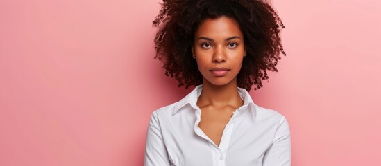 Portrait of a young woman with curly hair wearing a stylish white shirt in a studio photoshoot - obrazy, fototapety, plakaty