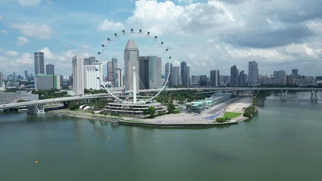 Drone wide shot of Singapore Flyer Eye, camera orbiting around Marina Bay F1 track with Singapore Airlines branding on corner 1. Singapore skyscrapers, Helix Bridge, Suntec City in background
