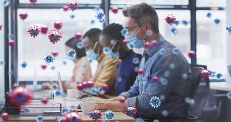 Fototapeta na wymiar Image of virus cells floating over diverse business people with face masks in office