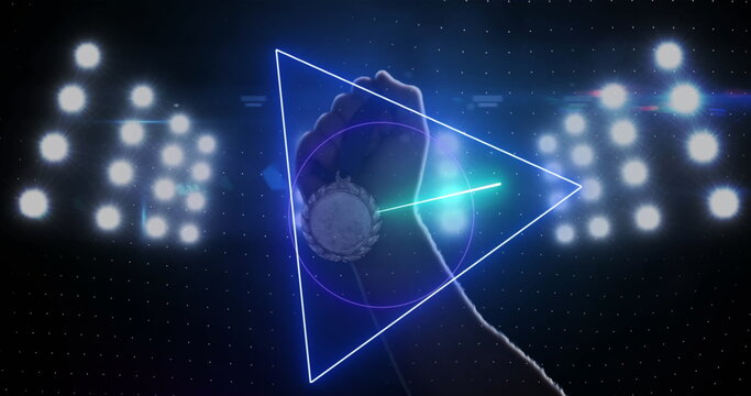 Image of purple neon scanner processing data over hand holding medal in floodlit sports stadium