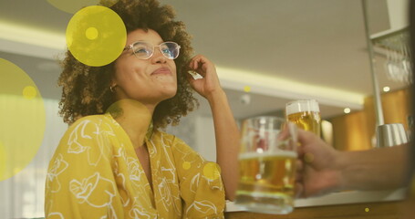 Image of spots over happy biracial woman with caucasian friend drinking beer - Powered by Adobe