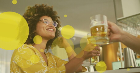 Image of spots over happy biracial woman with caucasian friend drinking beer