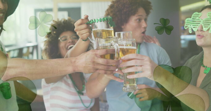 Image of clovers over diverse friends smiling and drinking beer