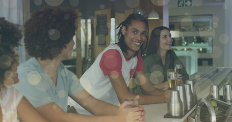 Image of light spots over smiling diverse friends watching tv and drinking beer