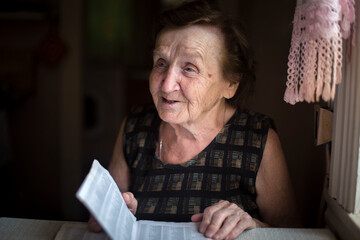 Grandma reading a newspaper at the table. - 740489911
