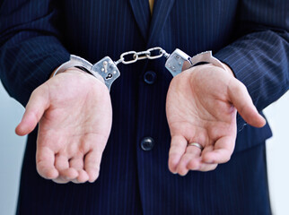Hands, person in business and handcuffs for fraud or bribery, suspicious professional deal with...