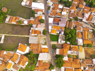 Aerial view of houses and rice fields in Bandung City, capital of West Java Province, Indonesia. Landscape view of rice fields squeezed by dense settlements. Shot from a drone flying 200 meters high.