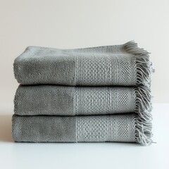 stack of warm grey knit sweaters on white background