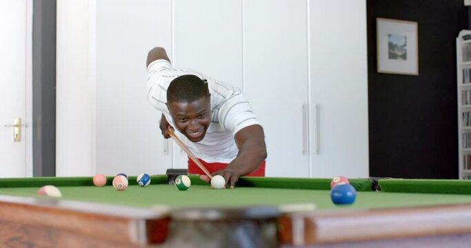 Young African American man playing pool at home