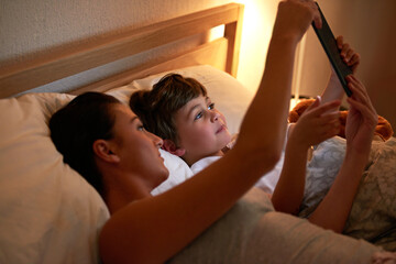 Mother, boy and tablet in bedroom at night for care, bonding or to watch movies together in family...