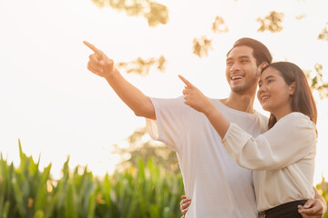 couple teen standing happy smiling together park outdoors sun shining hand pointing high for life...