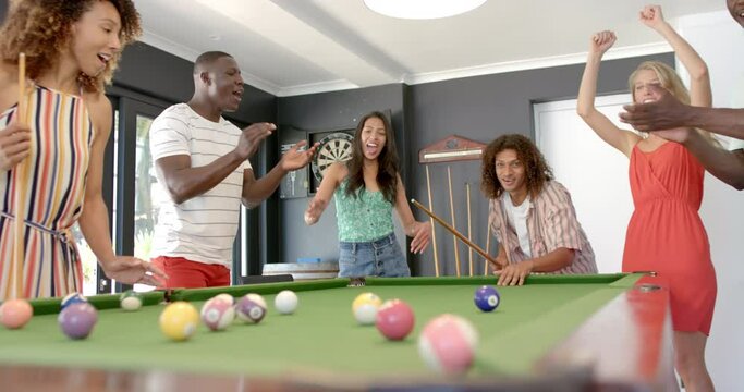 Diverse friends enjoy a game of pool at home