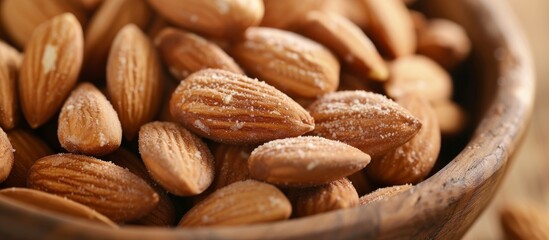 Obraz premium A wooden bowl filled with almonds, a staple food, sits on a table, showcasing natural foods and the use of plant ingredients in cuisine