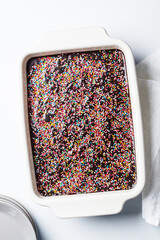 Classic chocolate cake with colored sprinkles in baking dish.