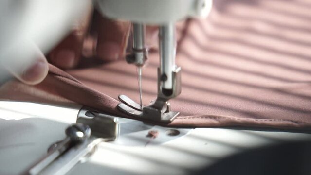 close up of tailor sewing pink cloth
