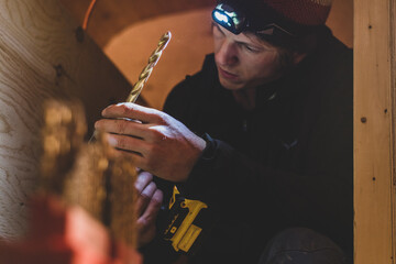 Man changing drill bit on power drill before making hole in wood