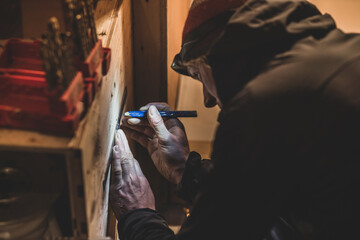 Close-up of man preparing to drill in wood in low light with headlamp © Cavan