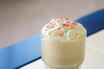 A milkshake with caramel stands in a glass on a table