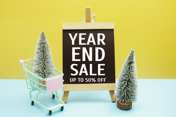 Year End Sale text message on chalkboard easel stand with Christmas tree decoration
