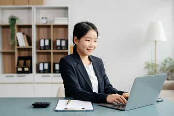 Young beautiful woman typing on tablet and laptop while sitting at the working white table