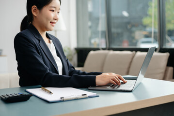 Young beautiful woman typing on tablet and laptop while sitting at the working white table
