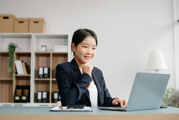 Young beautiful woman typing on tablet and laptop while sitting at the working white table