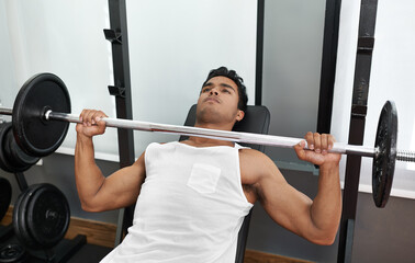 Fototapeta premium Bench, press and man at gym for exercise, workout and body building in Mexico. Healthy, person and weightlifting challenge for strong muscle, fitness or progress in training arms with barbell in club