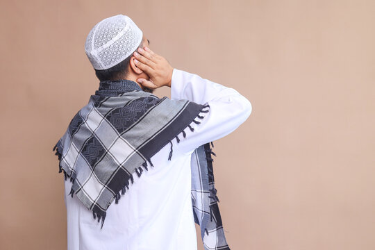 Back view of religious Muslim man doing the call to prayer or iqamah over beige background
