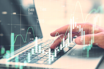 Close up of businessman hand using laptop at desk with growing forex chart on blurry background. Financial investment and economy concept. Double exposure.