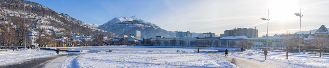 Wide panorama of Lille Lungegårdsvannet or lake in the central bergen in winter, covered with snow and ice. Visible cityscape of Bergen in Sunny weather.