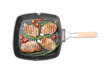 Grill pan with delicious pork steaks, garlic, chili pepper and rosemary isolated on white, top view